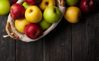 Fruits de pomme mûrs colorés dans un panier sur une table en bois.