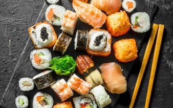 Délicieux petits pains, sushis et makis sur une planche en pierre avec des baguettes.