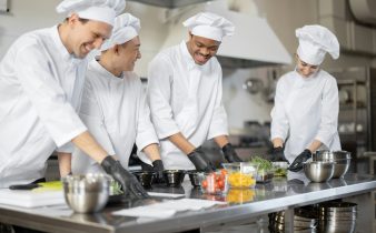 Équipe multiraciale de cuisiniers mélangeant des ingrédients pour les plats à emporter dans une cuisine professionnelle.