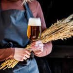 Brewer en tablier contient du verre de bière et des épillets de blé