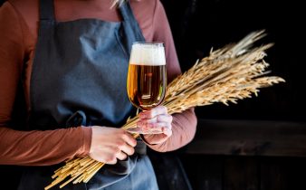 Brewer en tablier contient du verre de bière et des épillets de blé