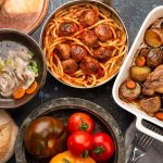 Table à manger avec plats traditionnels de savoureux maison: soupe de poulet, boulettes de viande avec spaghettis, poulet rôti avec pommes de terre.