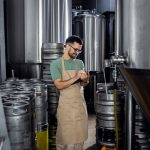 Homme travaillant dans la brasserie artisanale examinant la production de la bière.