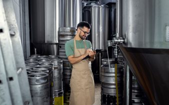 Homme travaillant dans la brasserie artisanale examinant la production de la bière.