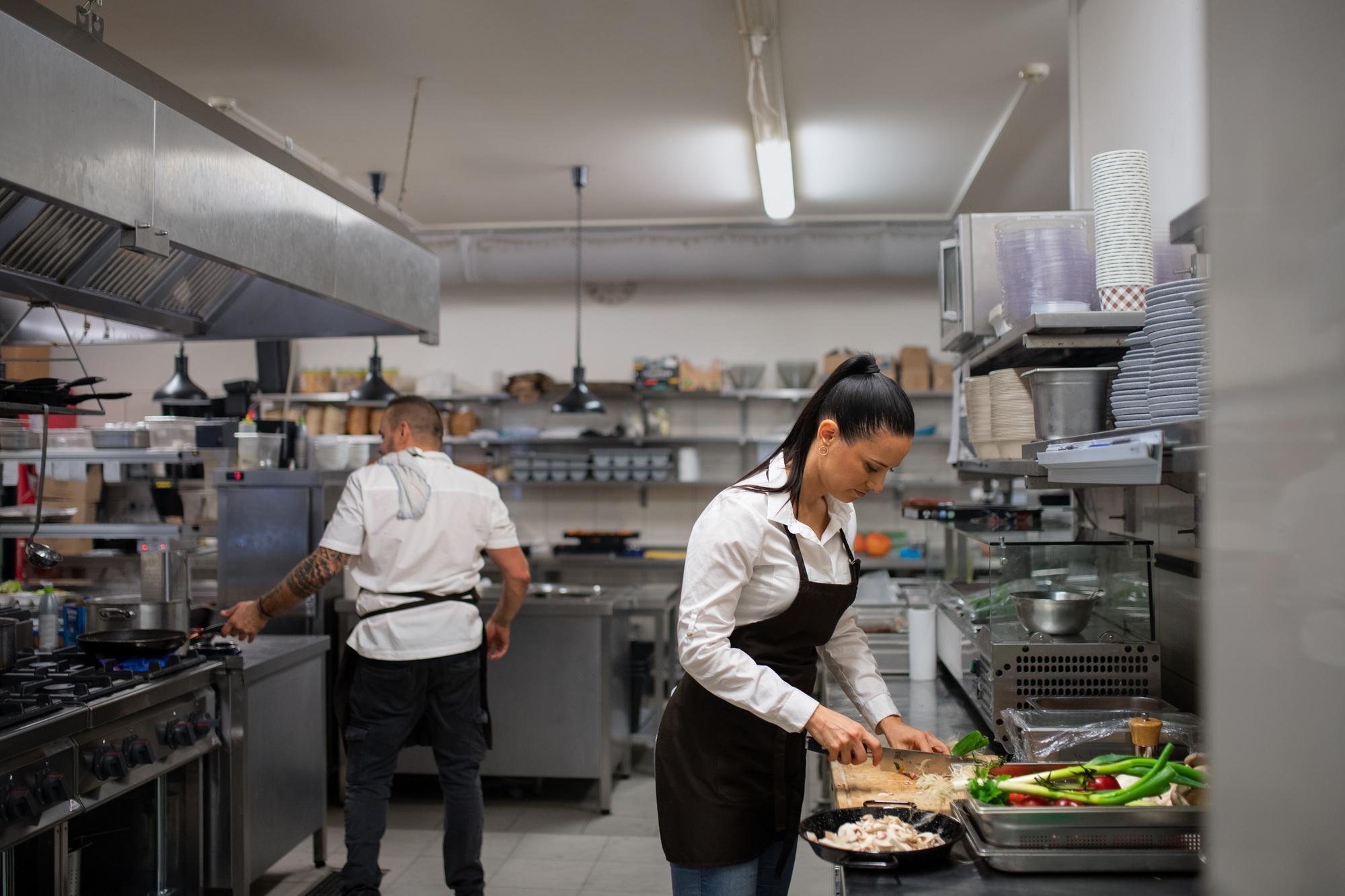Une femme professionnelle coupant les légumes à l'intérieur dans la cuisine du restaurant.