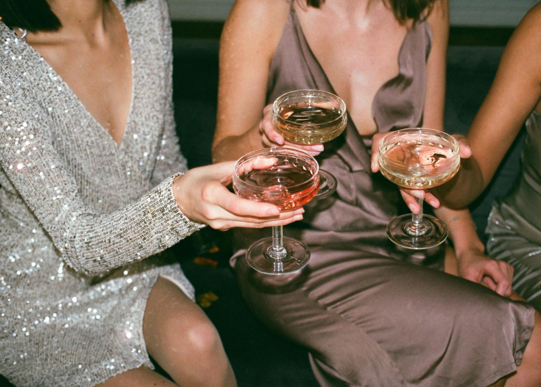 Trois femmes en robes élégantes grillant avec du champagne lors d'un rassemblement festif.