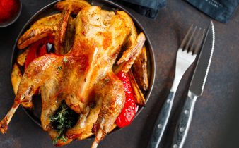 Volaille d'Inde rôtie avec des herbes et de l'huile d'olive sur un plat avec une garniture de pommes de terre et du poivron rouge.