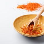 Épices de safran sec traditionnelles dans une assiette sur table blanche avec un espace de copie