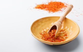 Épices de safran sec traditionnelles dans une assiette sur table blanche avec un espace de copie