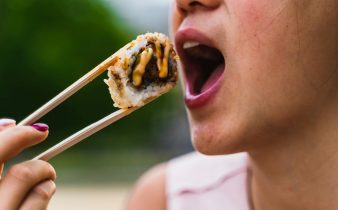 Femme mangeant des sushis avec des baguettes à l'extérieur, présentant des photographies culinaires vibrantes.