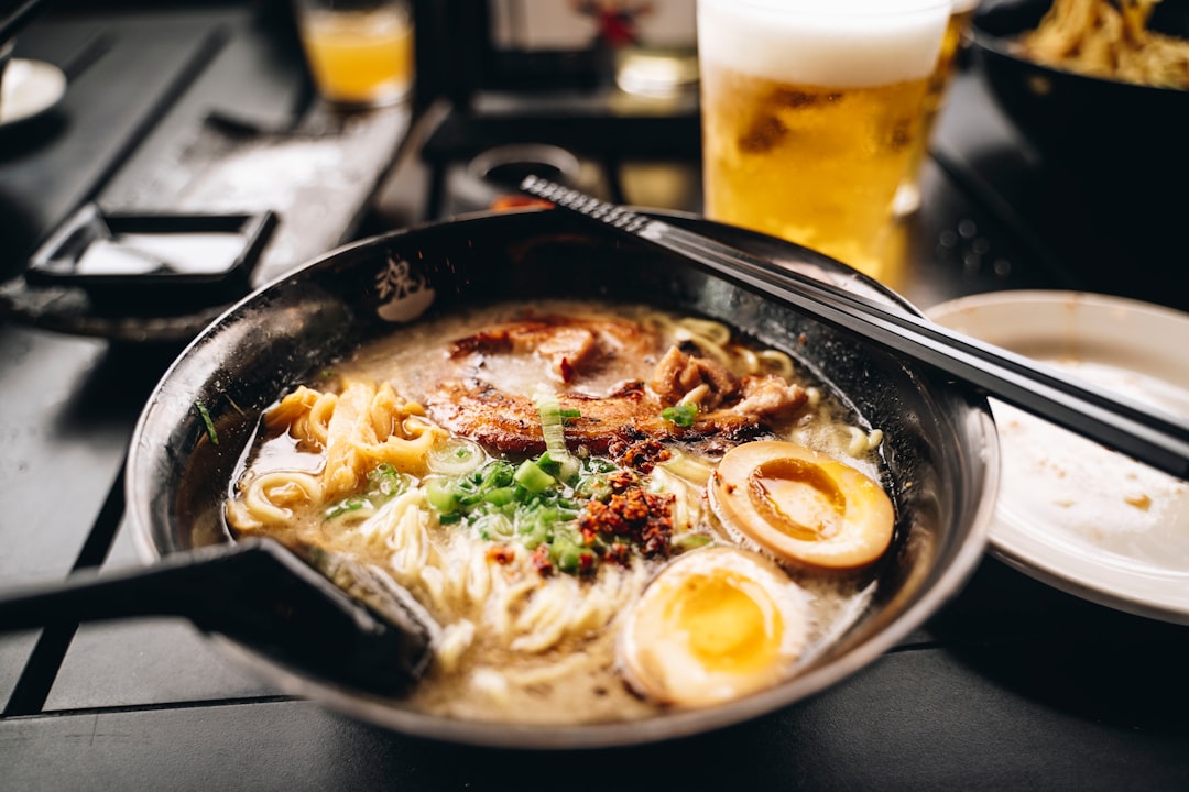 un bol de ramen avec des baguettes et un verre de bière