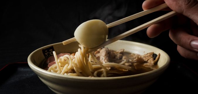 Gros plan sur d'authentiques nouilles ramen avec un œuf dur et des baguettes. Idéal pour les passionnés de gastronomie.